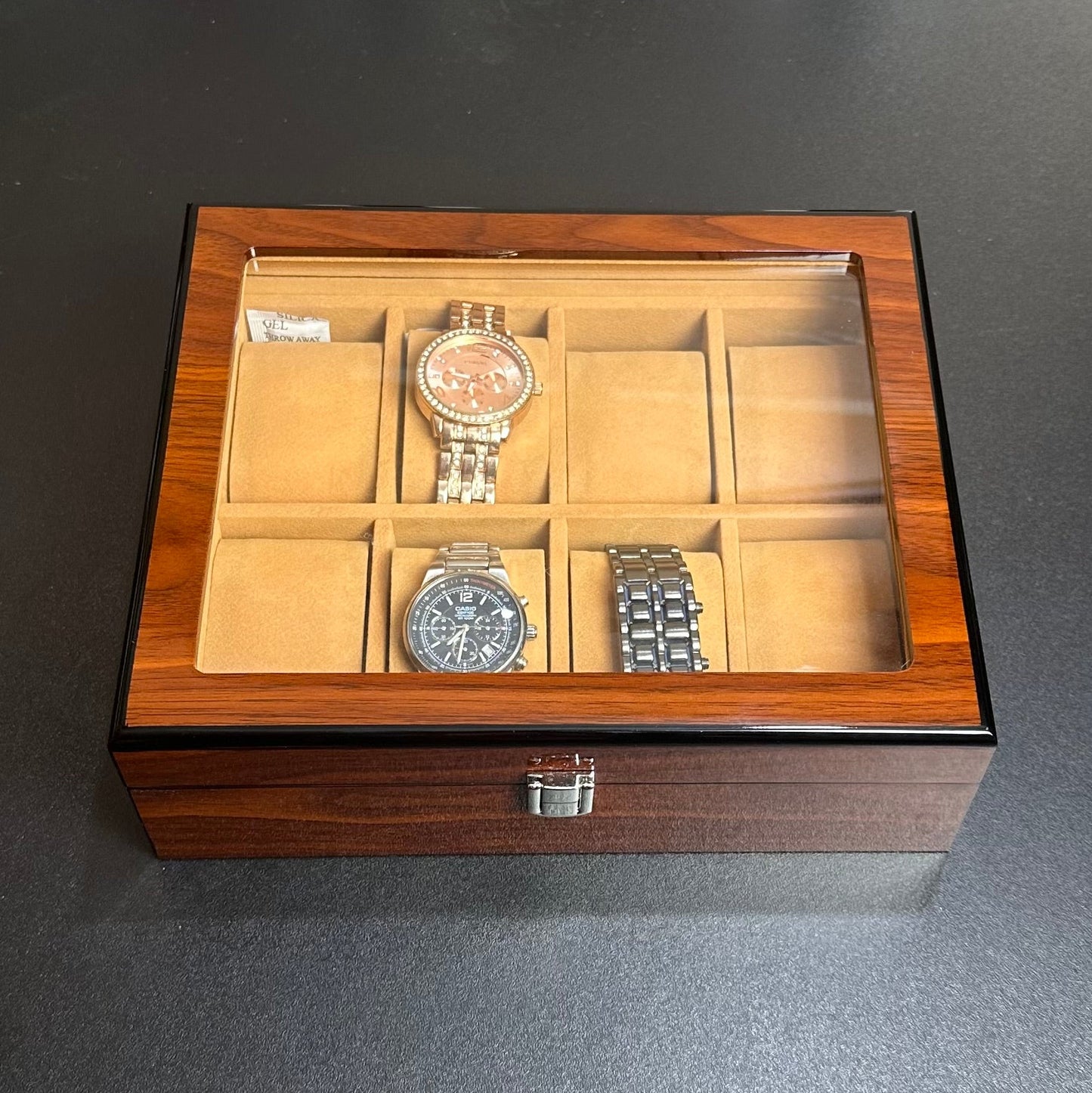 Wooden watch box with three watches on a dark surface