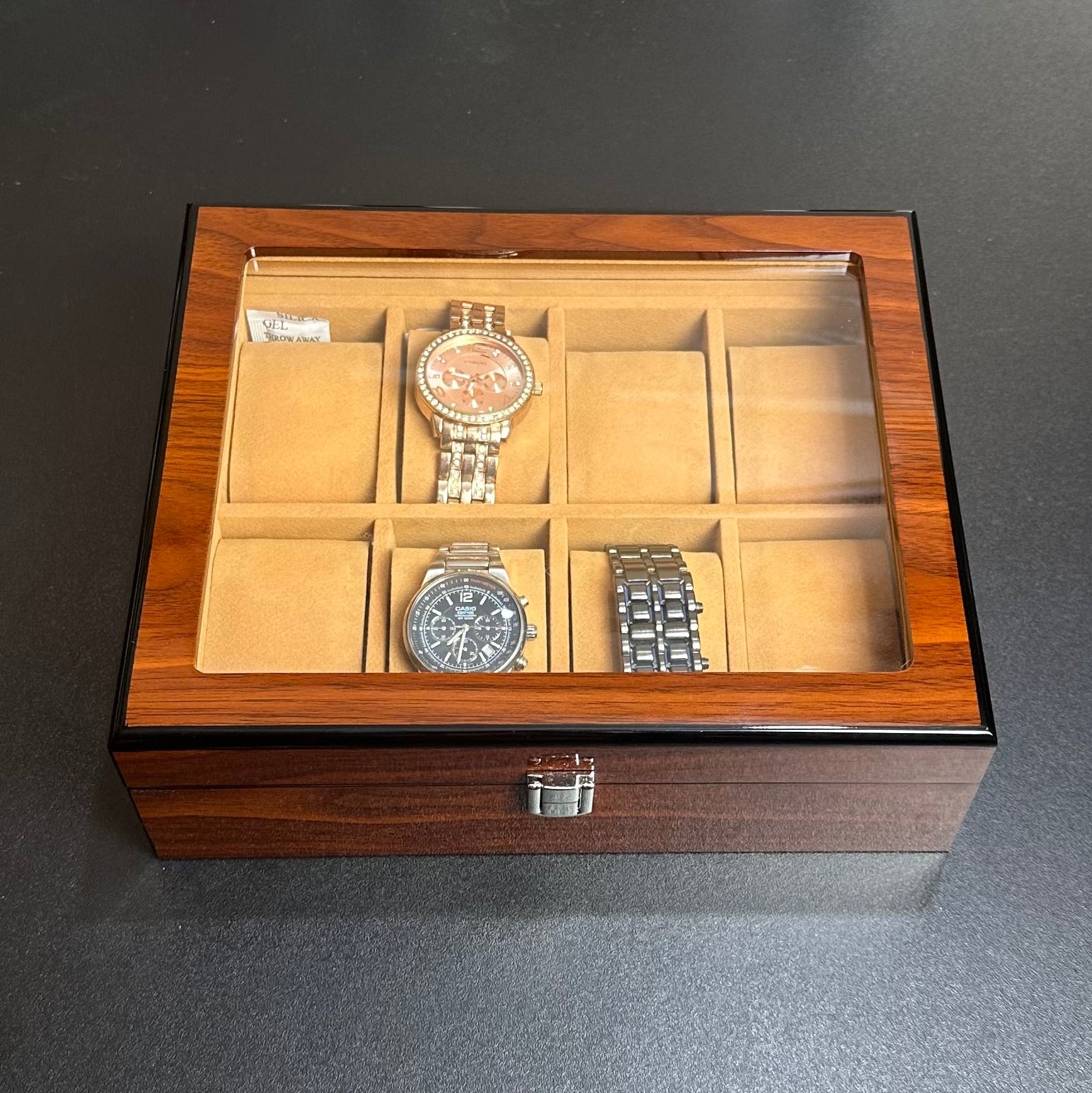 Wooden watch box with three watches on a dark surface