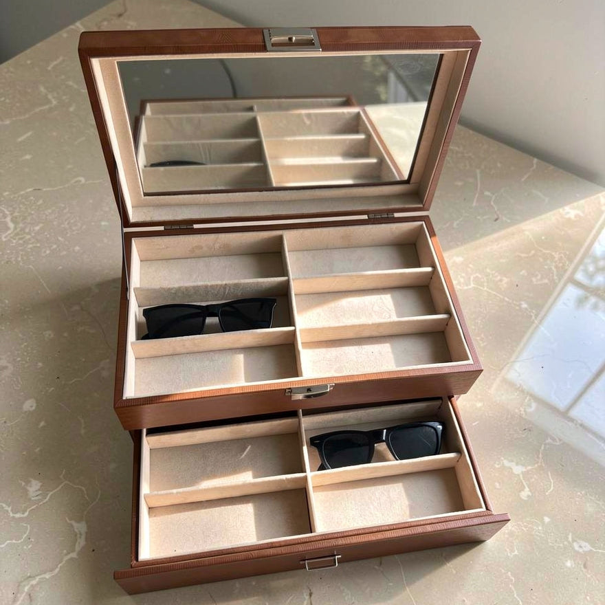 Wooden jewelry box with sunglasses inside on a marble surface